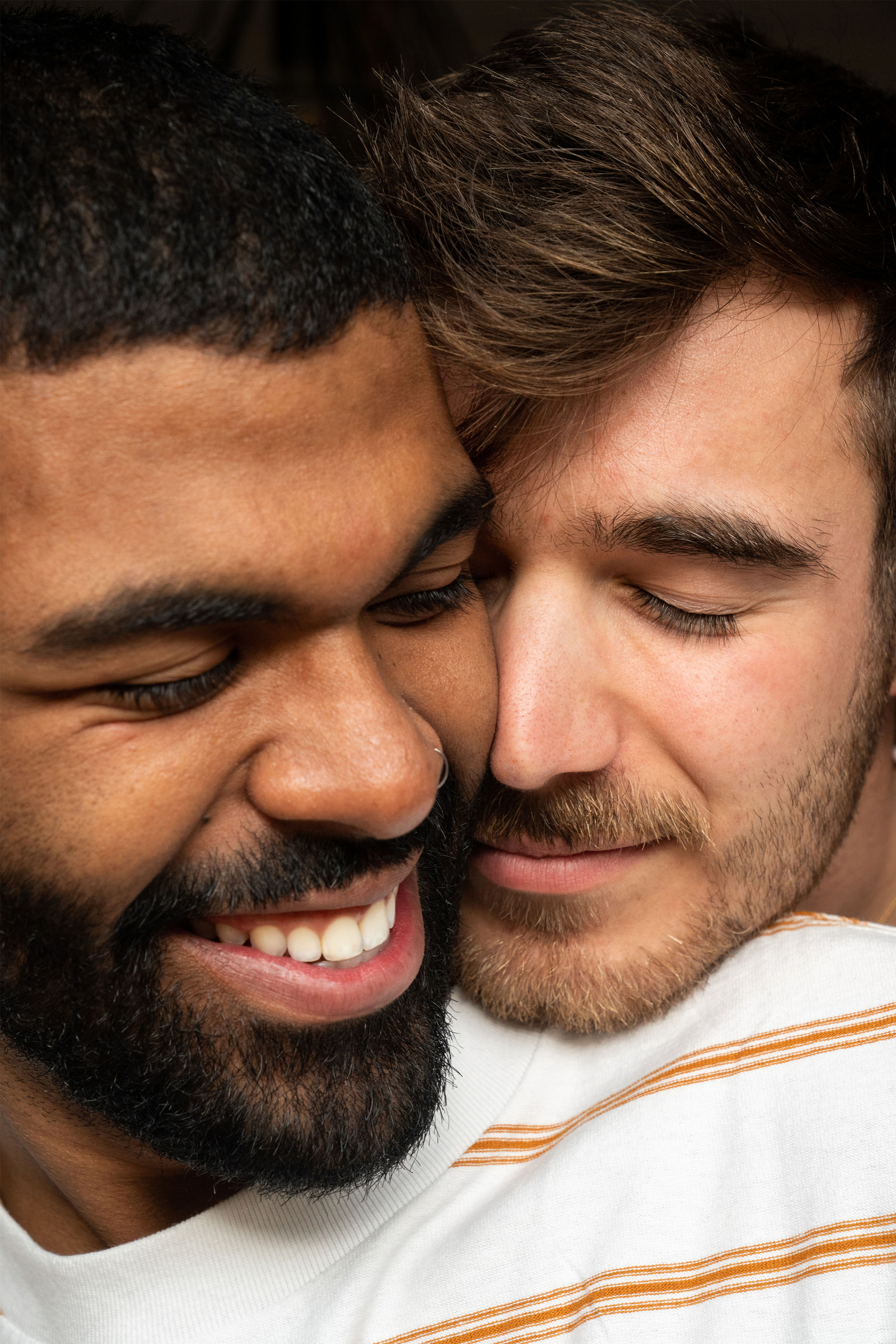 Two men smiling with their faces pressed together.
