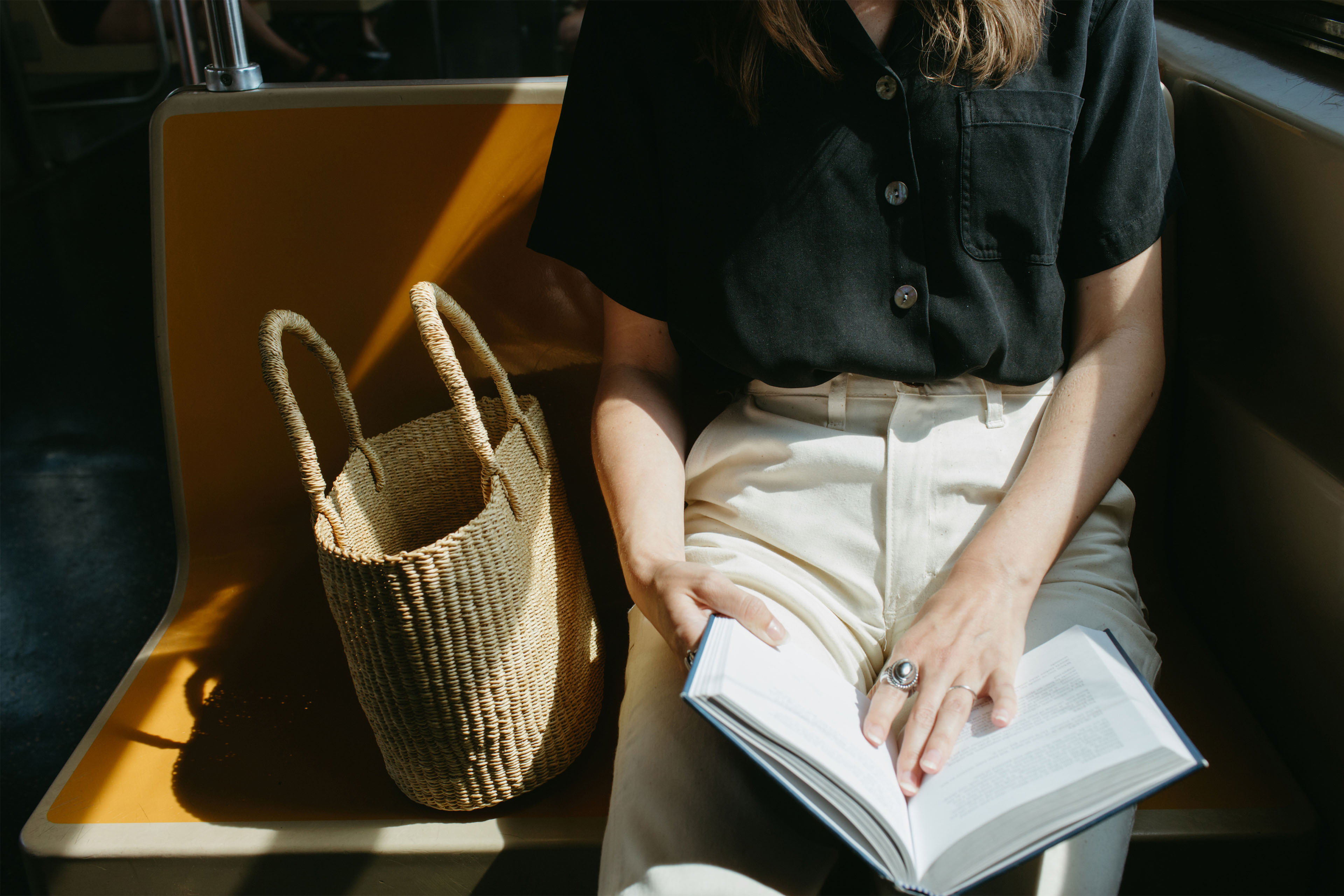 A woman on a train seat with a book open on her lap.
